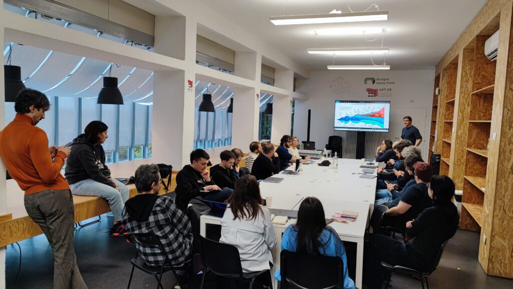 Foto di gruppo durante un workshop aziendale in una sala riunioni moderna con schermo e partecipanti attenti.