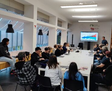 Foto di gruppo durante un workshop aziendale con un relatore che mostra grafici su schermo a Bologna Game Farm.