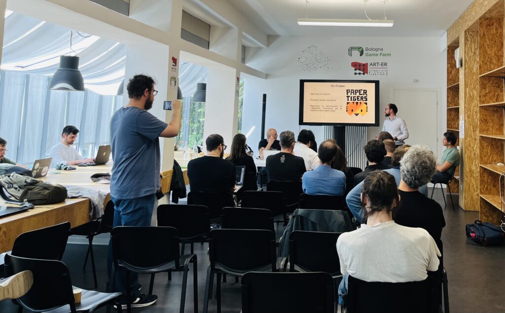 Presentazione di Paper Tigers al Bologna Game Farm con pubblico in sala e relatore alla lavagna luminosa.